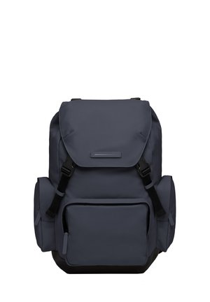 Sac à dos gris en tissu durable, équipé d'une fermeture à rabat, de bretelles réglables, d'une poche frontale et de poches latérales pour un rangement supplémentaire.