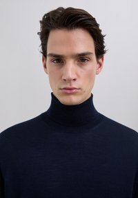 Suéter cuello alto de color azul marino hecho de un material de punto fino, con un diseño ajustado y textura suave, sin patrones ni elementos visibles.