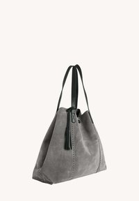 Sac tote en daim gris avec des sangles en cuir noir, présentant un détail en frange, un design spacieux et des accents couture pour une texture supplémentaire.