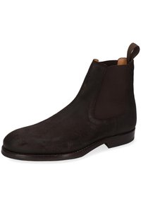 Bottine Chelsea en daim marron avec des panneaux élastiques sur les côtés, une pointe arrondie et un petit talon empilé. Présente une texture lisse et un matériel minimal.