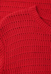 Tissu tricoté rouge avec des rangées alternées de motifs de mailles pleines et ajourées, présentant un col arrondi avec un bord côtelé.