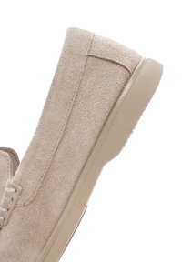 Beige suede slip-on shoe with a textured finish, rubber sole, and minimal stitching detail along the upper side.