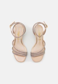 Sandalias de tacón alto con tiras, con una suela de charol nude. Acabadas con tiras metálicas entrelazadas, adornadas con rhinestones multicolores.