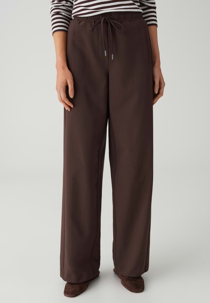 Pantalon marron à jambes larges avec une taille élastique, un cordon de serrage et une texture lisse. Assorti à un haut rayé à manches longues.