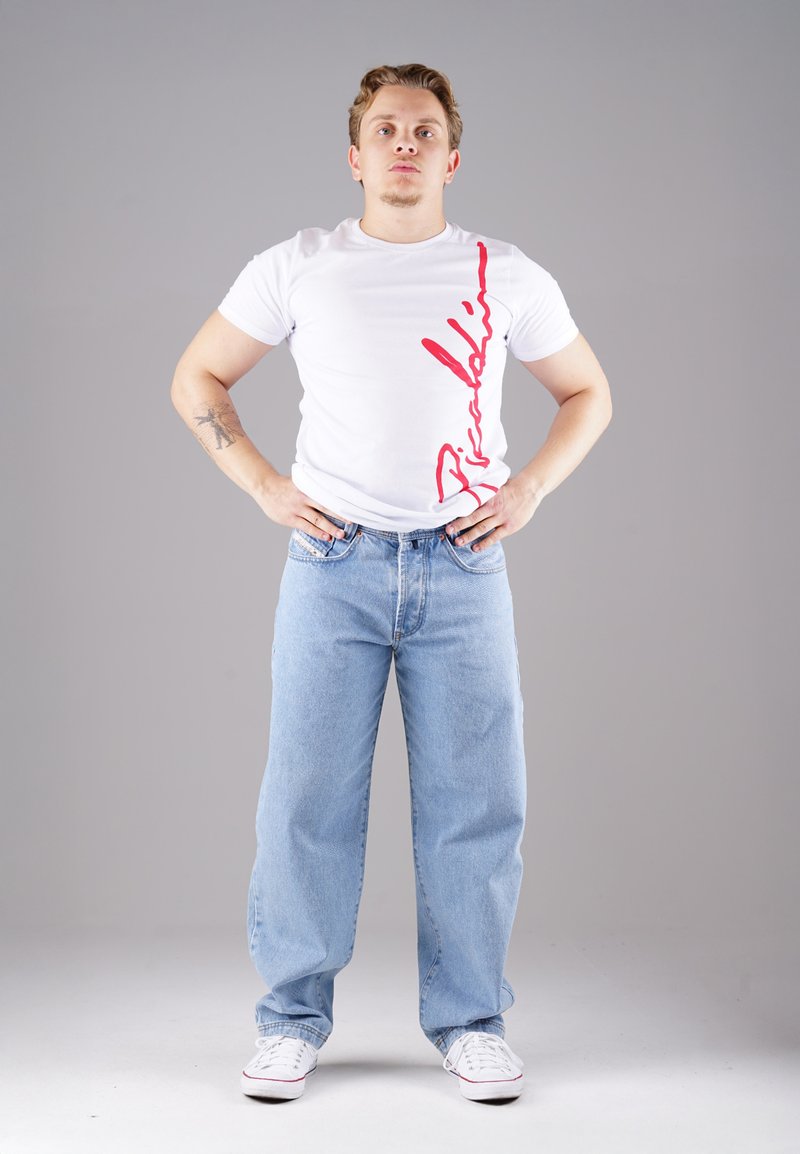 White T-shirt with red graphic on the left side, paired with light blue relaxed-fit jeans and white sneakers. Minimalistic design, casual look.