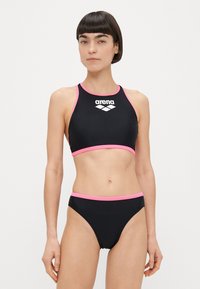 Μαύρο σετ μπικίνι που περιλαμβάνει crop top με υψηλό λαιμό και ροζ αποχρώσεις με λογότυπο, συνοδευόμενο από σλιπ με χαμηλή μέση και αντίστοιχη ροζ επένδυση.