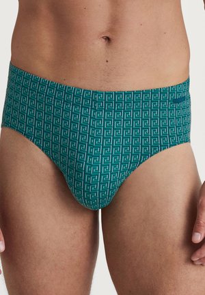 Türkisfarbene Schwimmslips mit einem geometrischen weißen Muster, ausgestattet mit einer glatten Textur und einem elastischen Bund für Komfort und Passform.