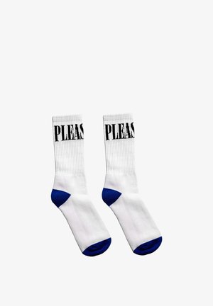 Białe skarpetki za kostkę z niebieskimi palcami i piętami, czarny napis „PLEASE” częściowo widoczny w pobliżu górnej krawędzi każdej skarpetki.