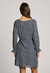 Blumenkleid in Marineblau mit langen Ärmeln und Rüschenmanschetten. Leichtes Gewebe mit weißen Blumenmustern, im lockeren Schnitt und mit Rundhalsausschnitt.