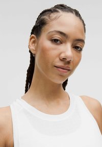 Witte sportieve tanktop met een gaasdetail, voorzien van een ronde halslijn en mouwloos ontwerp. Haar in vlechten gestyled.