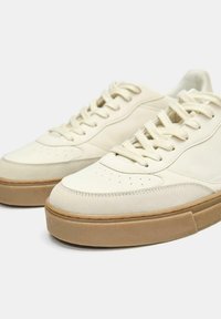 Off-white Sneakers mit einer glatten Lederoberfläche, strukturierten Akzenten, perforiertem Zehenbereich und einer Sohle aus Gummi. Mit flachen Baumwollschnürsenkeln.