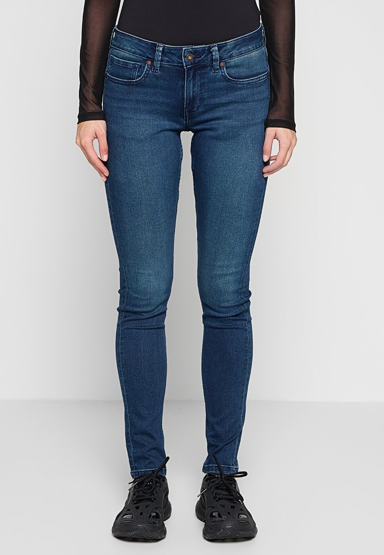 Jeans skinny blu scuro con vita media, design a cinque tasche e una leggera scoloritura. Il materiale sembra denim con lieve elasticità.