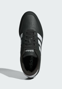 Čierna športová obuv s koženým zvrškom, s tromi bielymi pásikmi, okrúhlou špičkou a čiernymi šnúrkami; značkovanie na jazyku a vložke.