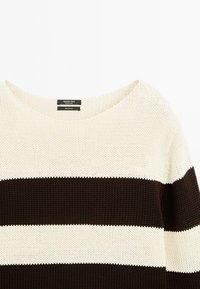 Knit sweater made of 100% cotton, featuring a wide scoop neckline, long sleeves, and alternating cream and dark brown horizontal stripes.