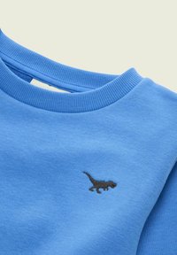 Blauwe crewneck sweatshirt met geribde kraag en klein zwart geborduurd dinosauruslogo op de borst.