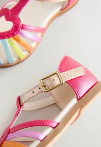 Gyermek szandálok rózsaszín fémes pánttal, csattal, többszínű szintetikus pántokkal és világosbarna talppal. Simább felület, szív mintával.