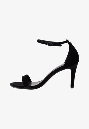 Musta korkokengän sandaali samettipinnalla, avoin varvas ja nilkkahihna, jossa on nappikiinnitys. Hoikka, kaareva korko.