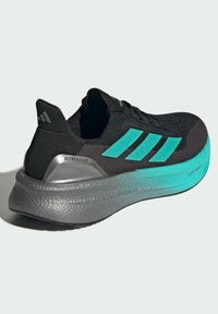 Scarpa sportiva nera con accenti turchesi, tomaia leggera e testurizzata, logo a tre strisce prominente e una suola spessa e ammortizzata grigia.