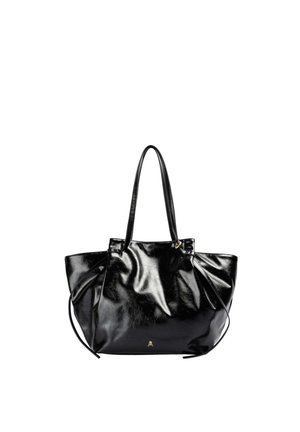 Bolso tipo tote de cuero negro y brillante con dos asas y un pequeño emblema dorado de calavera en el frente sobre un fondo blanco.