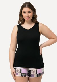 Schwarzes, ärmelloses Tanktop mit V-Ausschnitt und glatter Textur, kombiniert mit gemusterten Shorts in Pink, Schwarz und weißen Flecken.