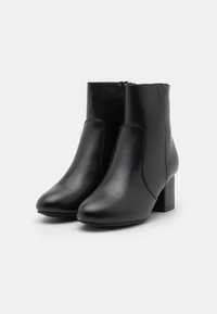 Svarta läderankelstövlar med en slät yta, rund tå och en blockklack. Har sidopaneler och en dragkedja för lätt på- och avtagning.