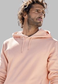 Hellrosa Kapuzenpullover mit Kordelzug, weichem Stoff und langen Ärmeln. Verfügt über eine Kängurutasche und gerippte Bündchen.
