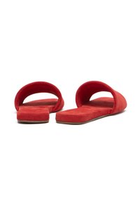 Infradito in suede rosso con suola piatta, design a ritaglio rotondo e texture morbida. Caratterizzano uno stile minimalista senza hardware visibile.