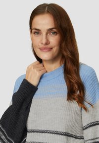 Gestrickter Pullover mit einem gerippten Textur, der einen Verlauf von blauen, grauen und schwarzen Streifen zeigt. Runder Ausschnitt und lange Ärmel.