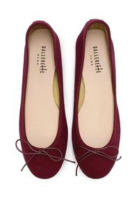 Ballerines en suède bourgogne avec un bout rond, un bord élastiqué et un nœud décoratif à l'avant. L'intérieur présente une semelle beige.