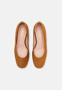 Ballerines en daim tan avec un bout arrondi, doublure intérieure lisse et accents minimaux. Design simple avec une semelle plate et sans détails en métal.