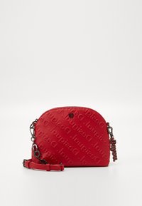 Sac à bandoulière en synthétique rouge avec un motif de logo embossé, forme arrondie, fermeture par zip et bandoulière amovible avec des accents en métal.
