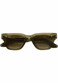 Lunettes de soleil avec une monture olive translucide, un design angulaire en forme de chat et des verres bruns dégradés. Présentent un logo discret sur les branches intérieures.