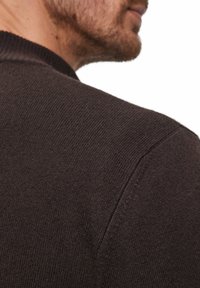 Maglione marrone scuro caratterizzato da un colletto a coste, una texture a maglia serrata e una vestibilità rilassata, mostrato di lato all'altezza della spalla.