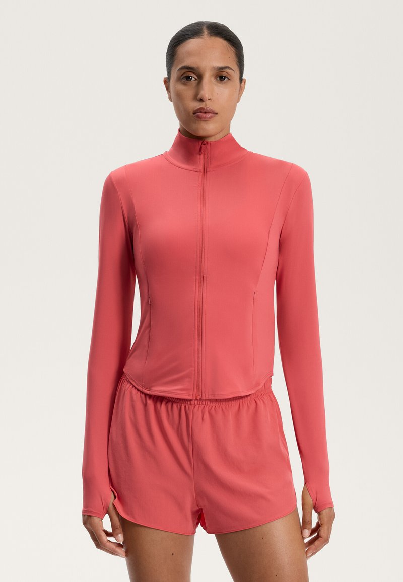 Coral athletic bodysuit with long sleeves, high collar, front zipper, and elastic waistband. Smooth texture, fitted design, no patterns.