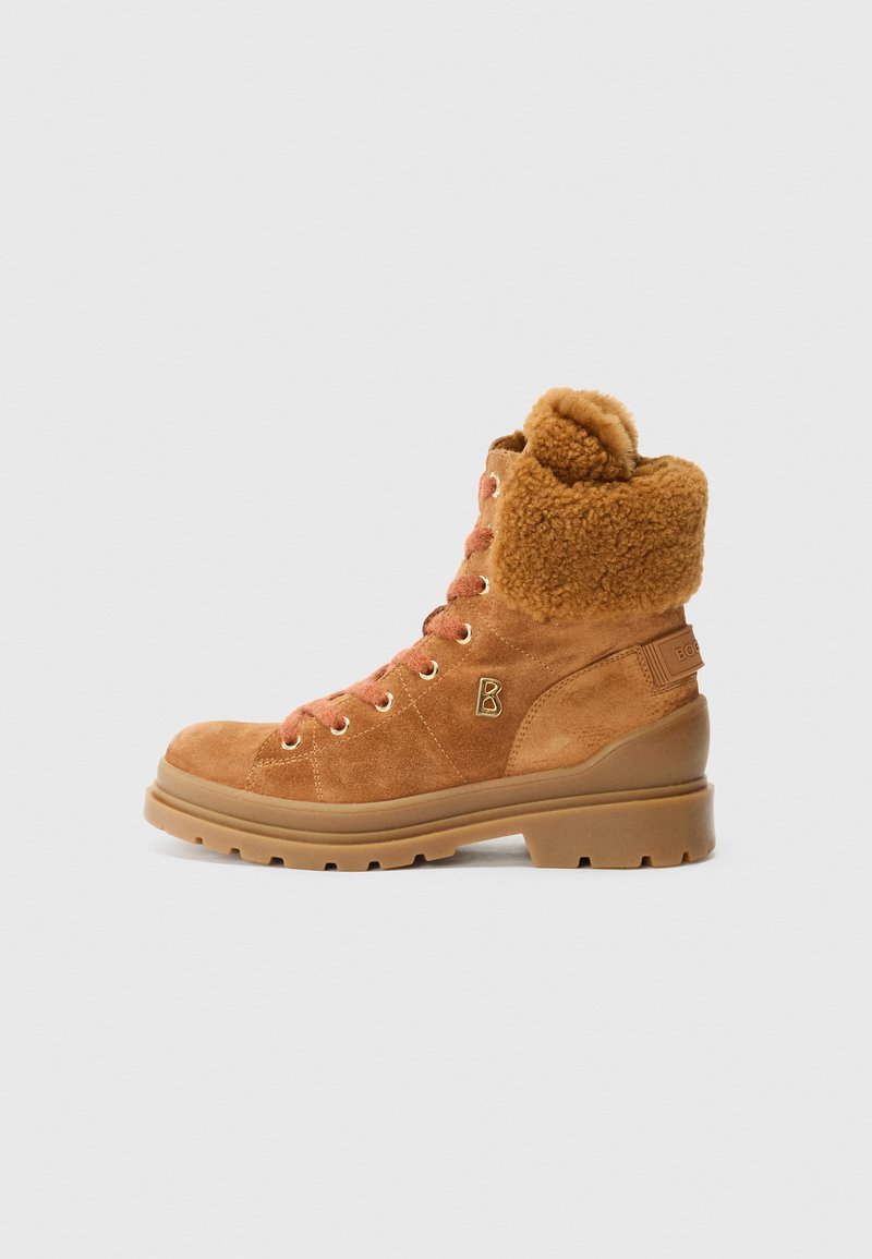 Botas de suede marrón con cordones, con una suela gruesa y un cuello forrado de piel, mostrando un diseño elegante y robusto sobre un fondo simple.