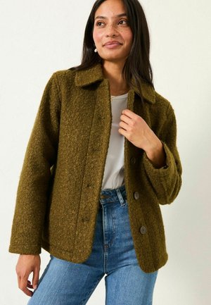 Olive green wool-blend jacket with a textured finish, button closure, and notched collar, paired with a white top and blue jeans.