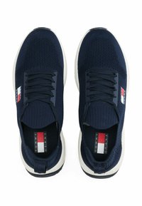 Baskets de sport navy avec un dessus en tricot texturé, semelle blanche et accents de logo en rouge, blanc et bleu. Conception à lacets avec un col rembourré.