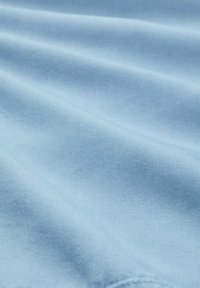 Lichtblauwe stof met een gladde textuur, die zachte plooien en een uniforme kleur toont. Geen zichtbare patronen of hardwaredetails.