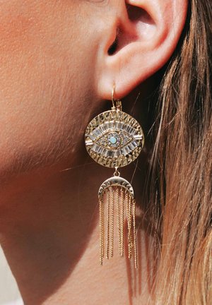 Goldene Anhängerohrringe mit einem Augendesign, das mit hellblauen Akzenten, rechteckigen Steinen und hängenden Ketten in einer Halbmondform verziert ist.