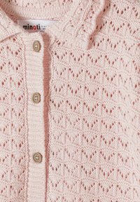 Cardigan bébé rose clair en tricot avec un motif ajouré en losanges et trois boutons beiges sur le devant.