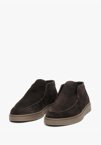 Ciemnobrązowe zamszowe botki za kostkę o minimalistycznym designie, z elastyczną podeszwą i subtelnymi detalami w postaci przeszyć wzdłuż krawędzi.