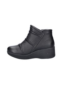 Zwarte leren enkelboots met een wiggenhak, voorzien van diagonale plooien en een rond neusstuk. Gladde textuur met rubberen buitenzool.