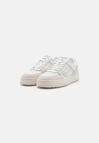 Leder- und Wildleder-Sneaker im Low-Top-Stil in Weiß und Hellbeige, mit durchlöchtem Zehenbereich, gepolstertem Kragen und dicker Gummisohle.