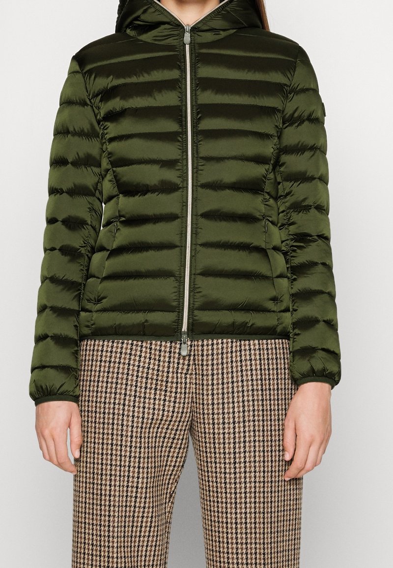 Grøn pufferjakke med hætte, der har vandret syninger, en frontlynlås og ribbede manchetter, parret med brune houndstooth-bukser.