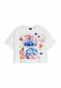 Vit kortärmad t-shirt med en blå tecknad karaktär med rosa accenter, omgiven av färgglada illustrationer av blommor och frukter.