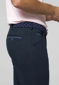 Marineblauwe broek met een soepele textuur, slim fit, zijzakken en een patroon geweven riem met donkerblauwe en lichtblauwe accenten.