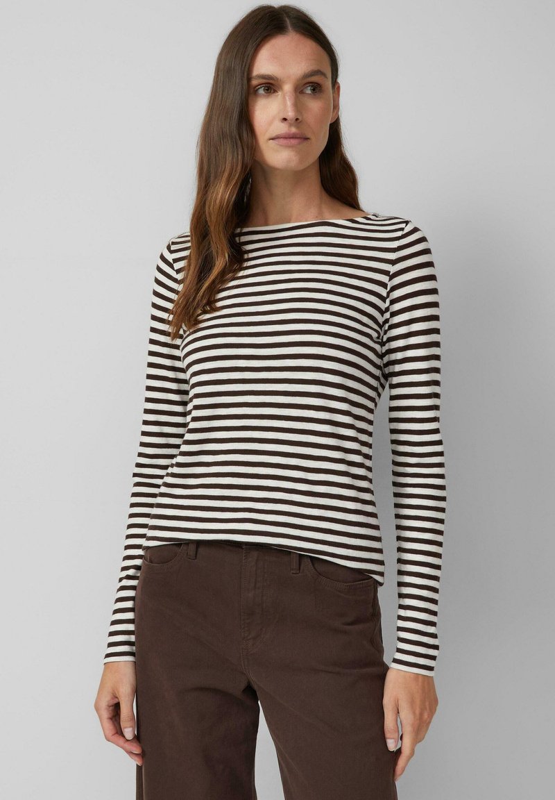 Gestreepte langekleurige top in crème en bruin, met een brede halslijn en aansluitende mouwen. Draagt met een donkerbruine broek.