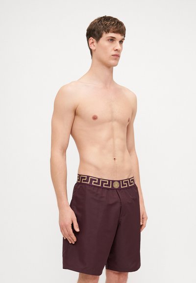 Σκούρο μπορντό μαγιό με υποαλλεργική ζώνη σε χρυσό σχέδιο, διαθέτει κορδόνι σύσφιξης και άνετη γραμμή. Κατασκευασμένο από ελαφρύ ύφασμα.