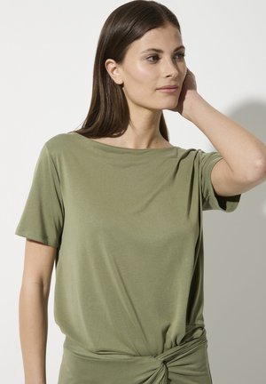 Olive green, short-sleeved top with a boat neckline and draped design; features a twisted knot detail at the waist, made of soft fabric.