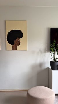 Dielo zobrazuje profilový portrét s veľkým čiernym afrom na béžovom pozadí. Izba obsahuje kvet v kvetináči a svetlý taburet.